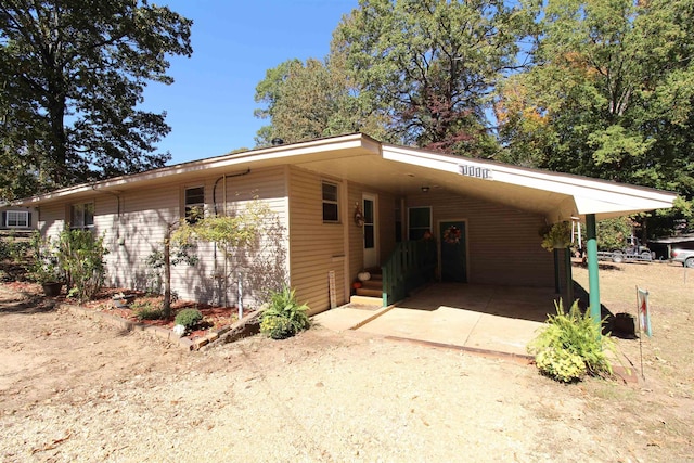 view of front of home featuring dirt driveway and an attached carport