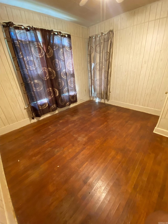 spare room with dark hardwood / wood-style floors and wooden walls