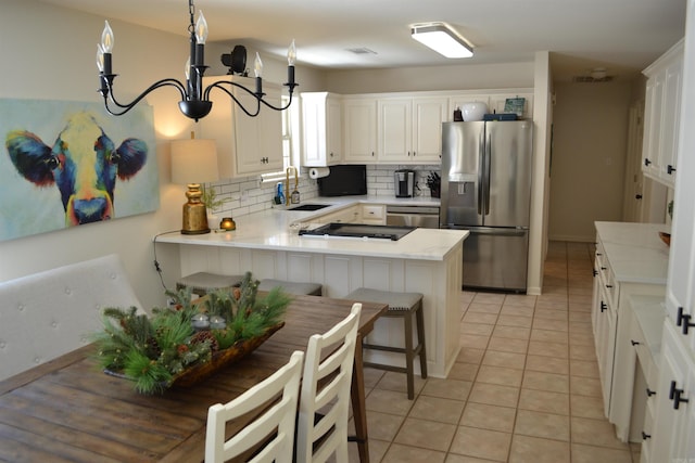 kitchen with appliances with stainless steel finishes, sink, a kitchen bar, kitchen peninsula, and white cabinetry