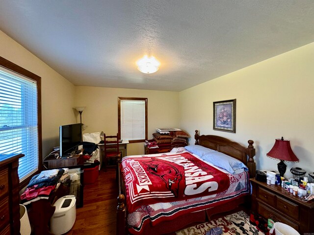 bedroom featuring a textured ceiling and dark hardwood / wood-style flooring