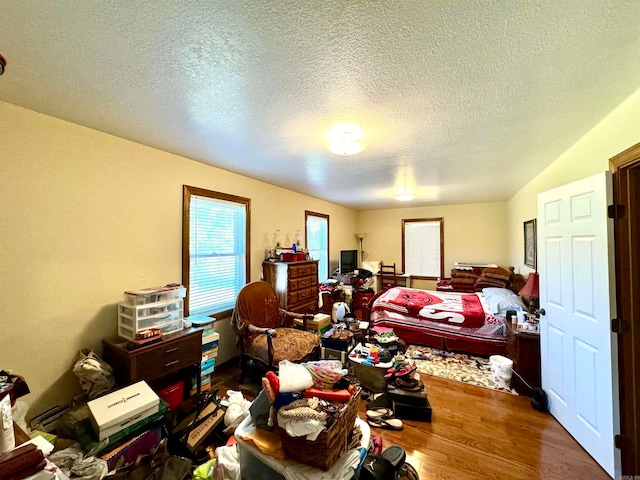 bedroom featuring a textured ceiling, vaulted ceiling, and hardwood / wood-style floors