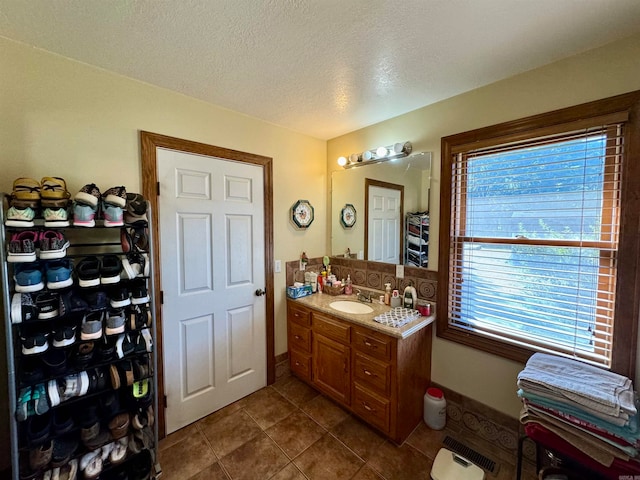 bathroom featuring vanity, a textured ceiling, a healthy amount of sunlight, and tile patterned floors