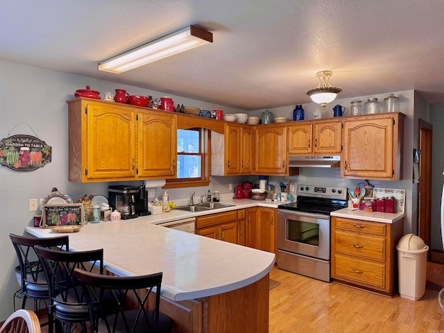 kitchen with sink, a textured ceiling, kitchen peninsula, stainless steel electric range oven, and light hardwood / wood-style flooring