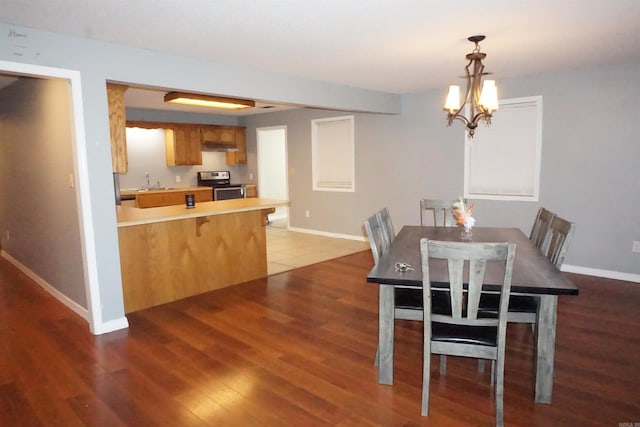 dining room with sink, a notable chandelier, and dark hardwood / wood-style flooring