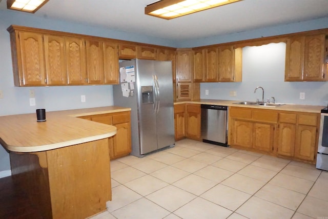 kitchen featuring light tile patterned floors, appliances with stainless steel finishes, sink, and kitchen peninsula