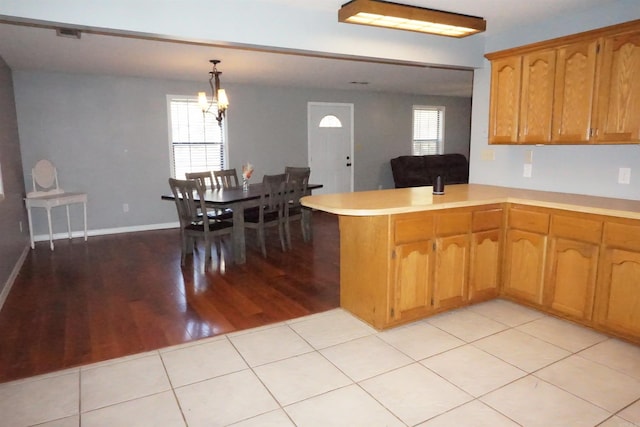 kitchen with a wealth of natural light, hanging light fixtures, kitchen peninsula, and light wood-type flooring