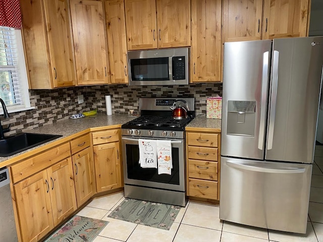 kitchen featuring sink, appliances with stainless steel finishes, tasteful backsplash, and light tile patterned flooring