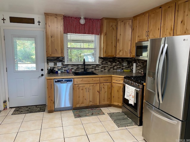 kitchen featuring appliances with stainless steel finishes, light tile patterned flooring, decorative backsplash, and sink