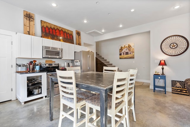 kitchen featuring appliances with stainless steel finishes, white cabinetry, and a kitchen breakfast bar