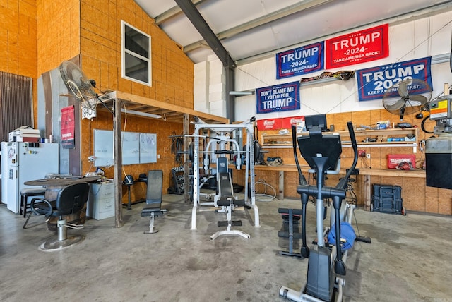 workout area with concrete flooring, a workshop area, and vaulted ceiling