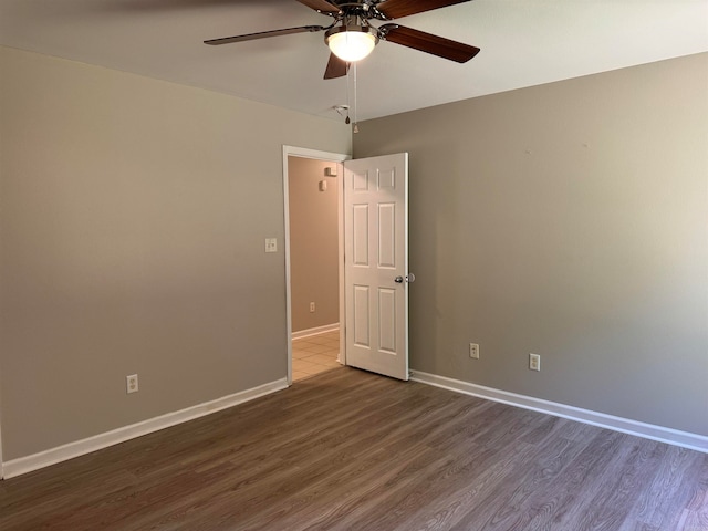 empty room with ceiling fan and dark hardwood / wood-style flooring