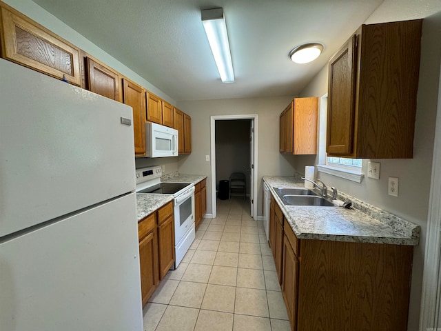 kitchen featuring sink, light tile patterned floors, and white appliances