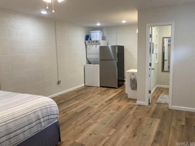 bedroom featuring stainless steel fridge, ensuite bath, and light wood-type flooring