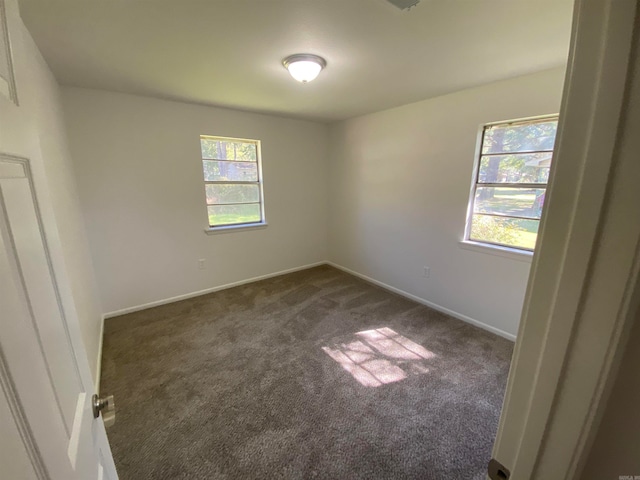 spare room with dark carpet