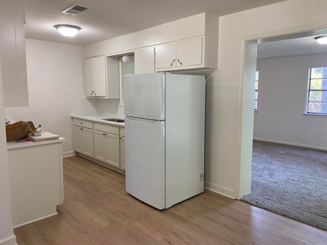 kitchen with light hardwood / wood-style floors, white refrigerator, and white cabinets