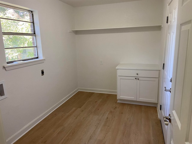 laundry room with electric dryer hookup, washer hookup, light hardwood / wood-style flooring, and cabinets