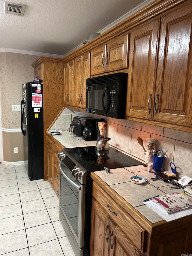 kitchen featuring black appliances, backsplash, a textured ceiling, crown molding, and light tile patterned floors