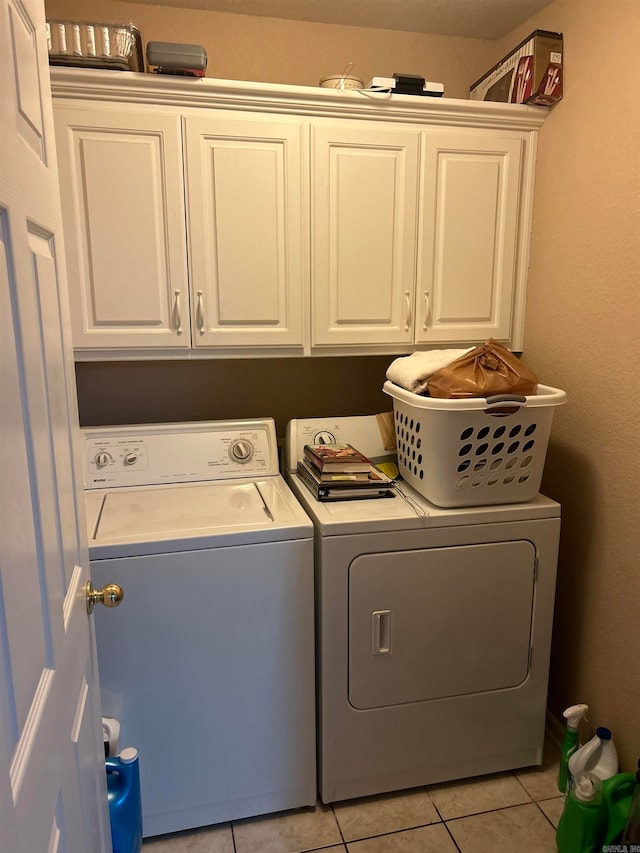 clothes washing area featuring light tile patterned floors, cabinets, and separate washer and dryer