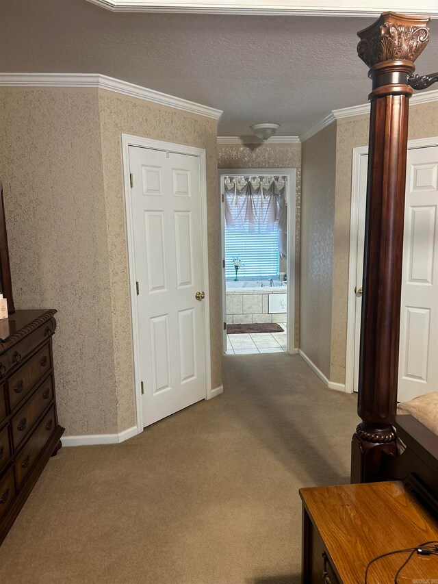 hallway with light carpet, ornamental molding, and a textured ceiling