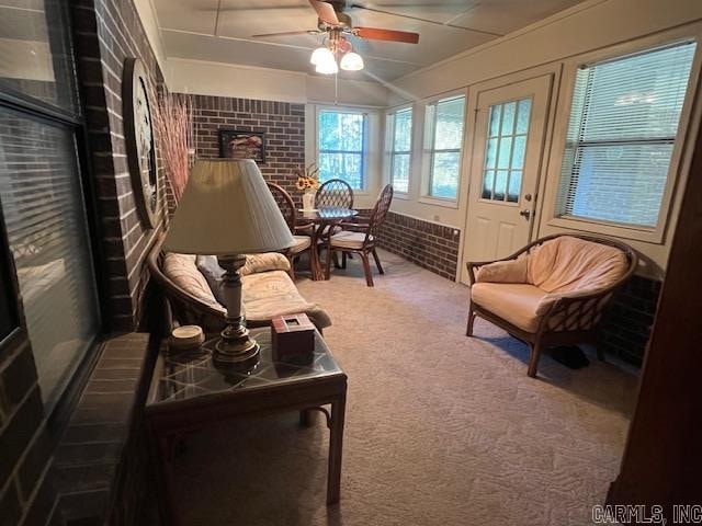 living area featuring carpet flooring, brick wall, and ceiling fan