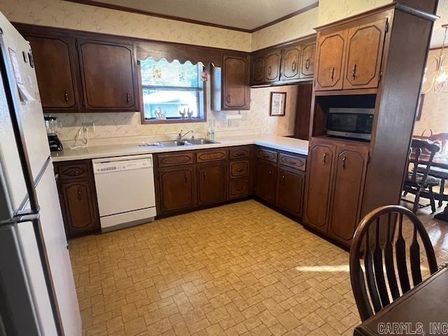 kitchen featuring ornamental molding, sink, dark brown cabinets, and white appliances