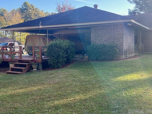 exterior space with a lawn, a wooden deck, and brick siding