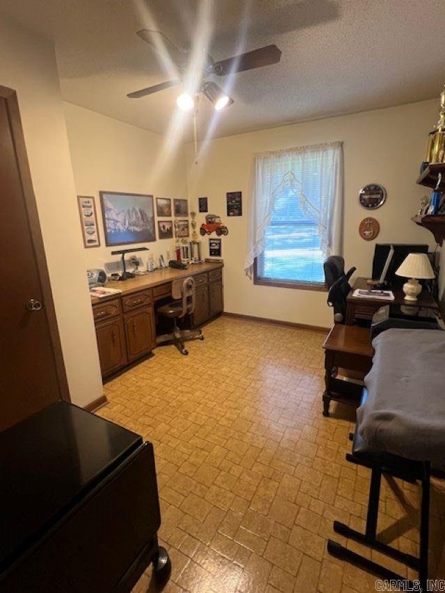 office featuring built in desk, a textured ceiling, and ceiling fan