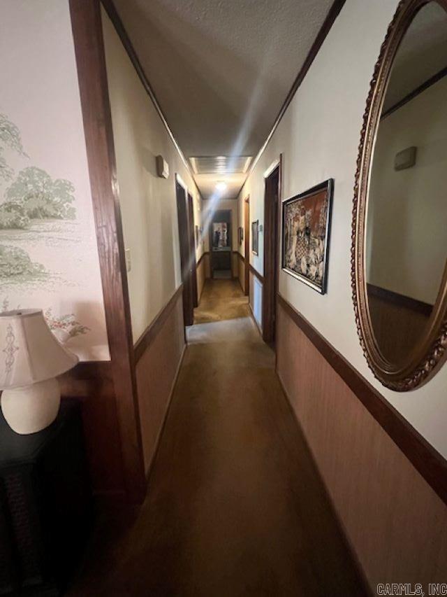 hallway featuring a textured ceiling and wooden walls