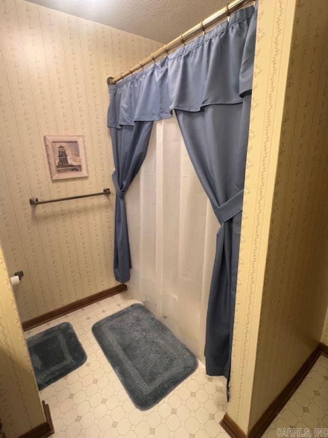 bathroom with a textured ceiling and a shower with shower curtain