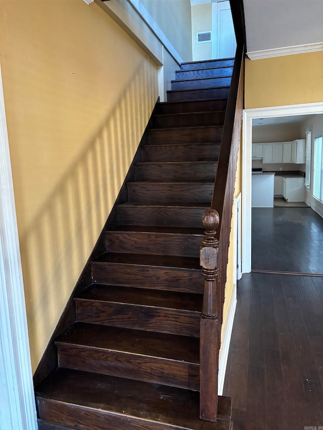 staircase featuring crown molding and wood-type flooring