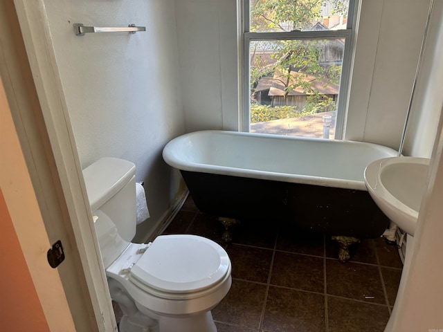 bathroom featuring toilet, a washtub, and tile patterned flooring