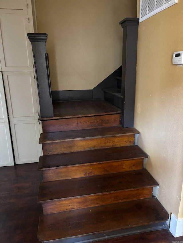 staircase with decorative columns and hardwood / wood-style floors