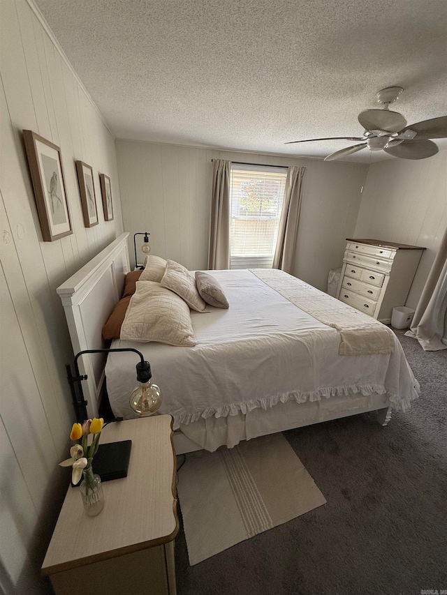 carpeted bedroom with a textured ceiling, wooden walls, and ceiling fan