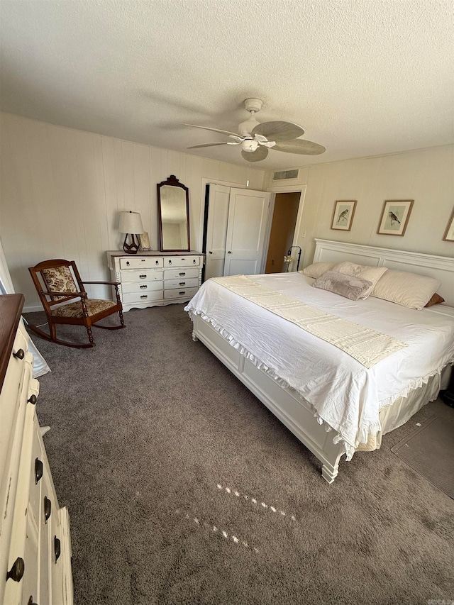 bedroom with dark colored carpet, a textured ceiling, a closet, and ceiling fan