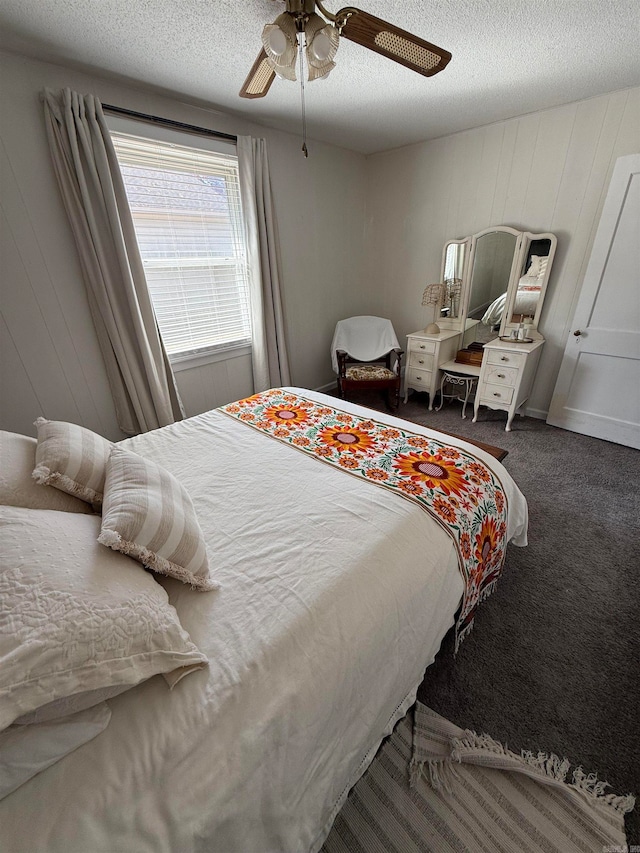 bedroom featuring ceiling fan, a textured ceiling, and dark colored carpet