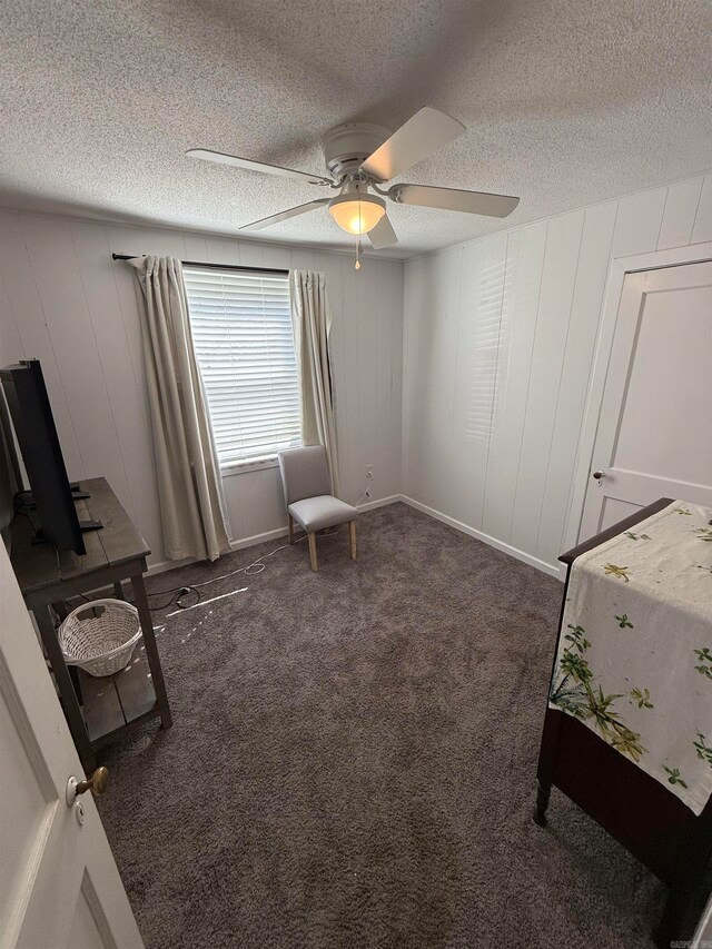 unfurnished bedroom with ceiling fan, a textured ceiling, and dark carpet