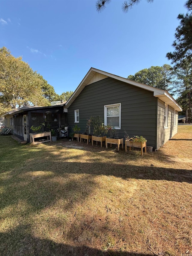 view of property exterior with a yard and a sunroom