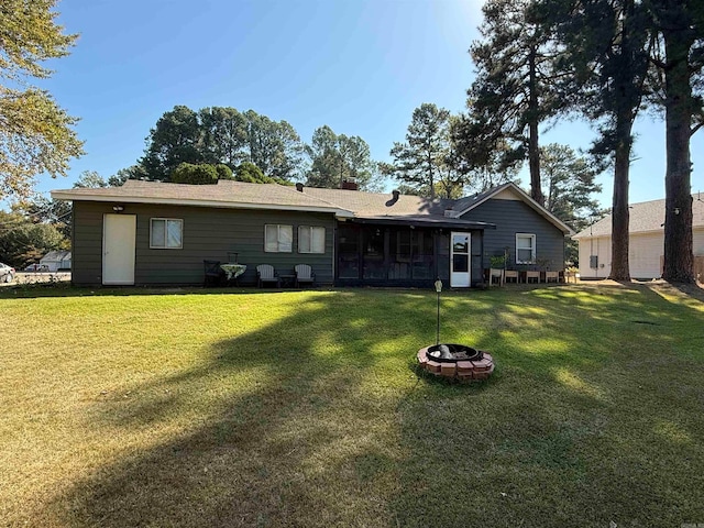 back of house featuring a lawn and a fire pit