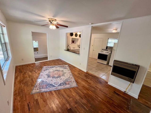 living room with heating unit, light wood-type flooring, and ceiling fan