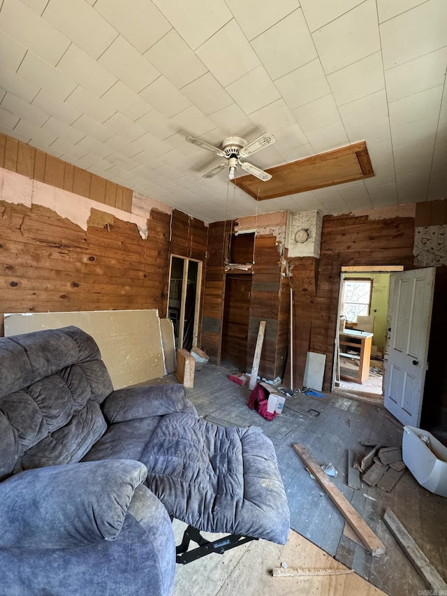 unfurnished living room featuring ceiling fan and wooden walls