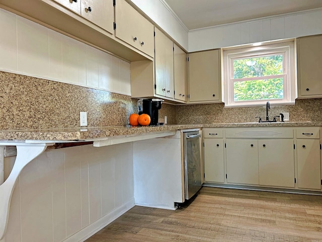 kitchen featuring cream cabinetry, light hardwood / wood-style flooring, backsplash, sink, and crown molding