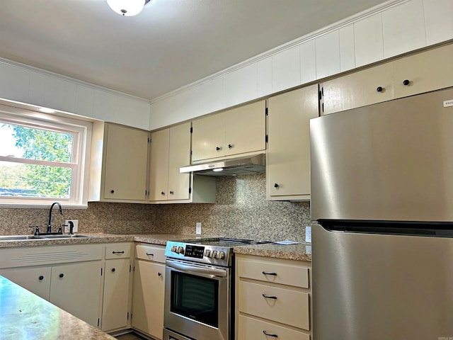 kitchen with cream cabinets, stainless steel appliances, sink, crown molding, and tasteful backsplash