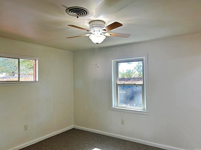 carpeted empty room with ornamental molding, a healthy amount of sunlight, and ceiling fan