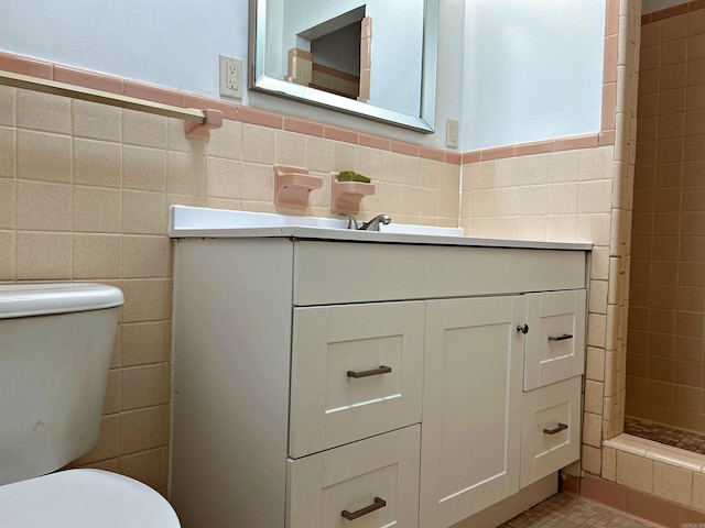 bathroom featuring tile walls, vanity, a tile shower, and toilet