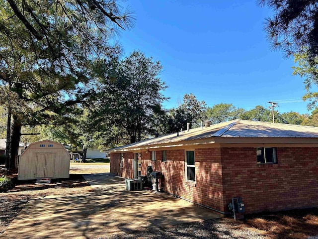 view of property exterior featuring central AC, a shed, and a patio