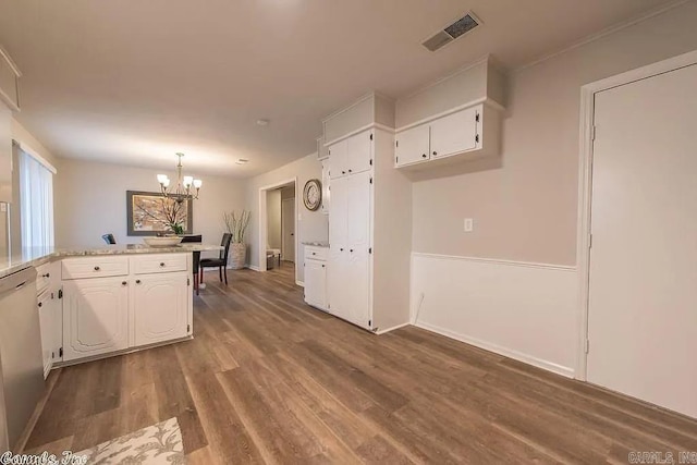 kitchen featuring light stone countertops, hardwood / wood-style floors, white cabinetry, stainless steel dishwasher, and a chandelier