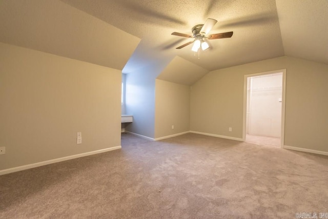 bonus room featuring lofted ceiling, carpet, a textured ceiling, and ceiling fan