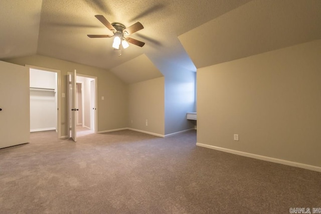 additional living space with ceiling fan, a textured ceiling, vaulted ceiling, and dark colored carpet