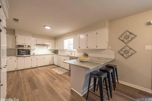 kitchen with sink, stainless steel oven, kitchen peninsula, and white cabinetry