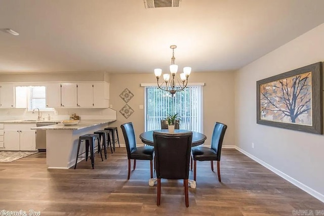 dining area featuring dark wood-type flooring and an inviting chandelier